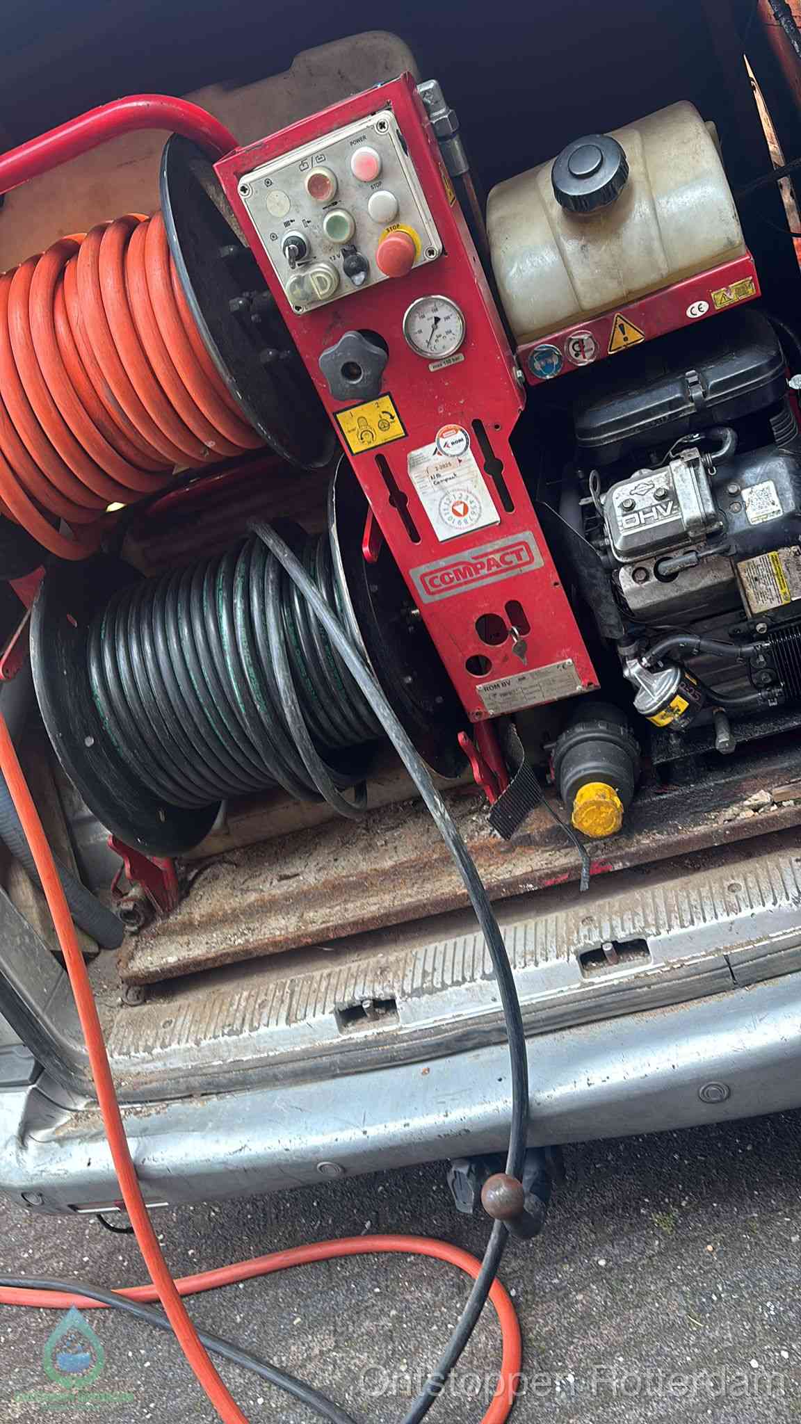 Een rood hogedruk-rioolreinigingstoestel met slangen in de laadbak van de bedrijfsbus, apparatuur voor een hardnekkige wc-verstopping in Rotterdam