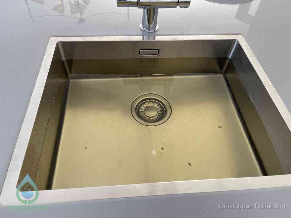 Stilstaand water in een rvs spoelbak dat niet wegloopt, een duidelijk signaal van een gootsteenverstopping in Rotterdam