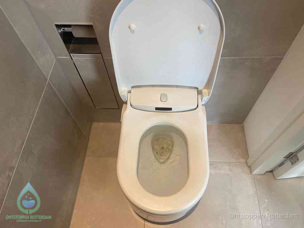 Een wit hangtoilet waarin een prop wc-papier op het water blijft drijven, een duidelijk signaal van een verstopte wc in Rotterdam