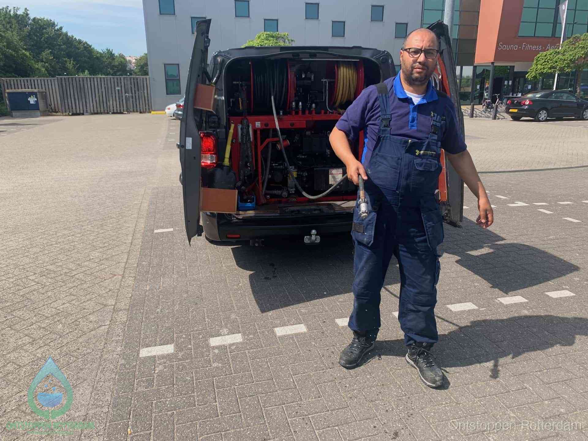 Een monteur bij zijn bestelbus met een hogedruk- en rioolreinigingsunit, klaar om de oorzaak van terugkerende wc-verstoppingen aan te pakken in Rotterdam
