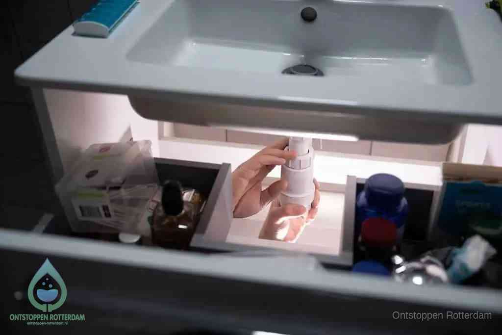 Een pompfles met zeep boven een wastafel in de toiletruimte, de warm water en afwasmiddel-methode om de wc te ontstoppen in Rotterdam