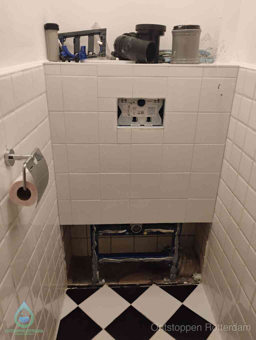 Een toiletruimte waar het hangtoilet en de inbouwreservoir-onderdelen zijn vrijgelegd voor onderhoud, periodiek nazicht voorkomt een wc-verstopping in Rotterdam